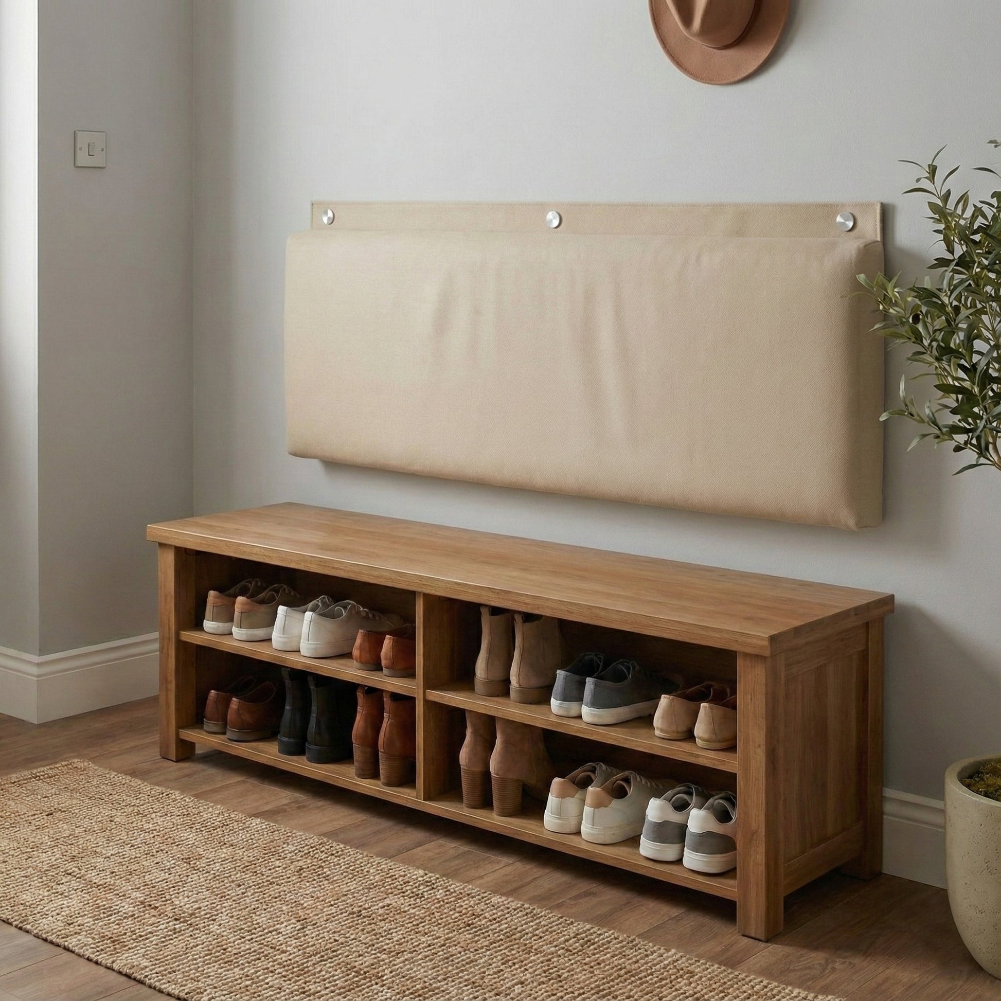 Rechteckiges, gepolstertes Wandkissen in Beige, das mit drei runden silbernen Metallkappen als Rückenlehne an der Wand über einer hölzernen Schuhbank montiert ist, um im Eingangsbereich Komfort zu bieten.